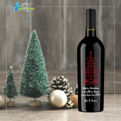 Garrafa de vinho com rótulo de Natal, árvores artificiais verdes, pinha e bolas douradas