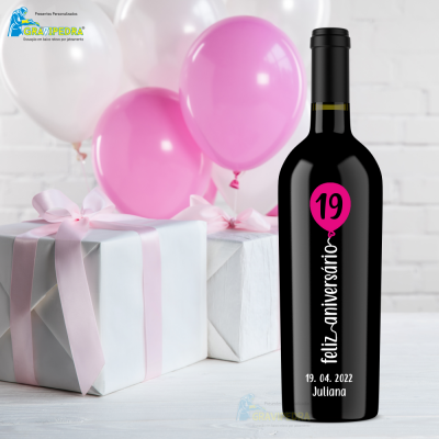 Garrafa de vinho preta decorada para aniversário com balão cor-de-rosa e textos em branco e presentes com laços numa mesa branca