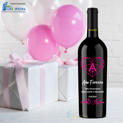 Garrafa de vinho com rótulo personalizado ao lado de presentes e balões rosa e branco