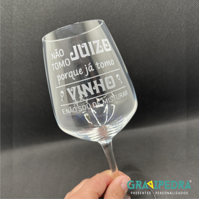 Copo de vidro para vinho com texto gravado em branco e fundo preto