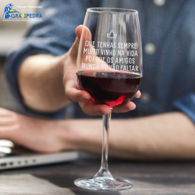 Copo de vinho tinto com texto em branco e mão a segurá-lo