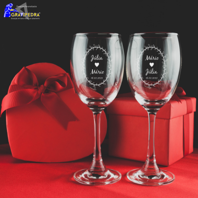 Dois copos de vinho gravados com nomes e duas caixas vermelhas de presente.