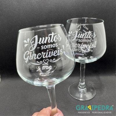 Duas taças de vidro gravadas, fundo preto.