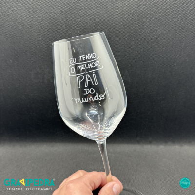 Taça de vidro transparente com texto branco gravado sobre fundo escuro