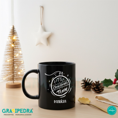 Caneca preta com texto natalício em mesa com decoração de Natal