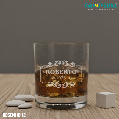 Copo de vidro com bebida castanha e texto personalizado, sobre madeira com amêndoas e dado branco