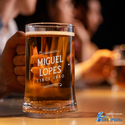 Copo de cerveja personalizado com texto 'MIGUEL LOPES SINCE 1980' em vidro transparente.
