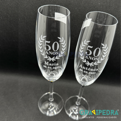 Dois copos de champanhe transparentes gravados com texto branco sobre fundo preto