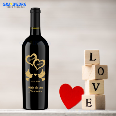 Garrafa de vinho preta personalizada com texto dourado e elementos românticos ao lado de coração vermelho e blocos de madeira com letras.