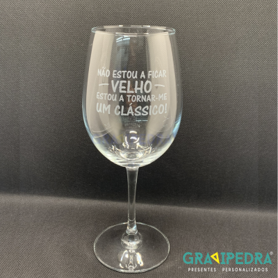 Copo de vinho transparente com texto gravado em branco e fundo preto