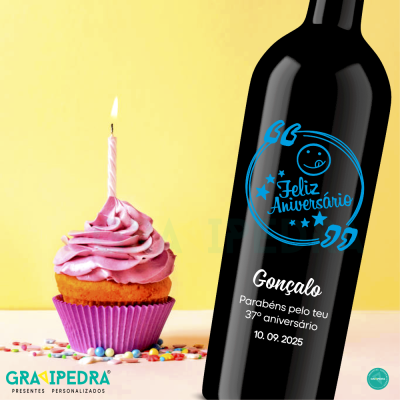Garrafa de vinho personalizada com texto de aniversário ao lado de cupcake com vela acesa