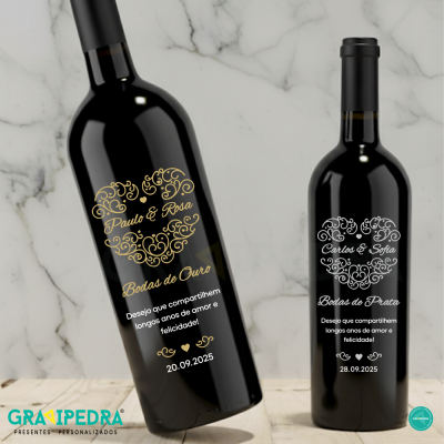Duas garrafas de vinho personalizadas com texto dourado e branco sobre superfície clara
