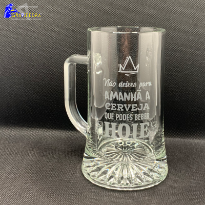 Caneca de vidro com gravação de mensagem em português em fundo cinzento.