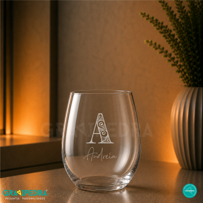 Copo de vidro gravado com letra A decorativa e nome Andreia ao lado de vaso com planta