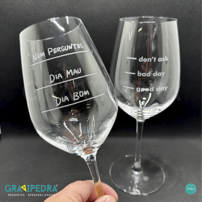 Dois copos de vinho transparentes com textos gravados em branco