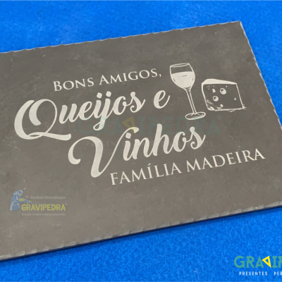 Placa de ardósia com texto sobre queijos e vinhos sobre fundo azul