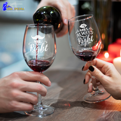 Dois copos de vinho tinto com textos personalizados, mãos segurando os copos, vinho sendo servido.