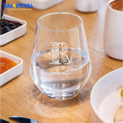 Copo de vidro decorado com letra R, água e comida em mesa de madeira