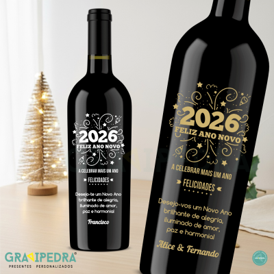 Garrafa de vinho preta personalizada com texto de Ano Novo 2026 em branco e dourado ao lado de uma pequena árvore decorativa iluminada.
