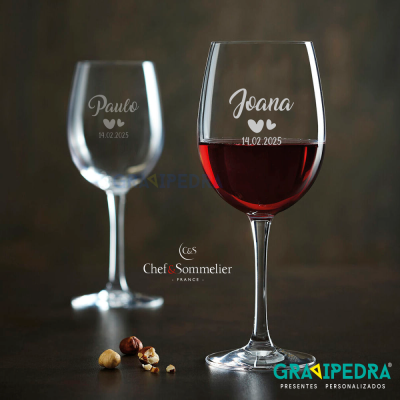 Dois copos de vinho personalizados com nomes e data sobre superfície com avelãs