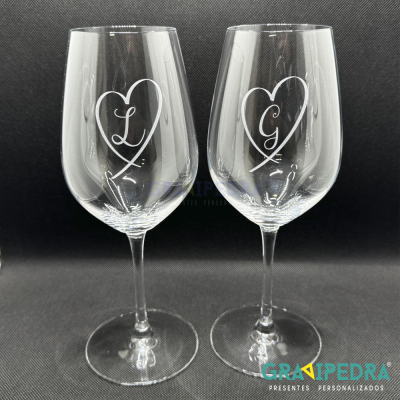 Dois copos de vinho transparentes com desenhos de coração e letras L e G