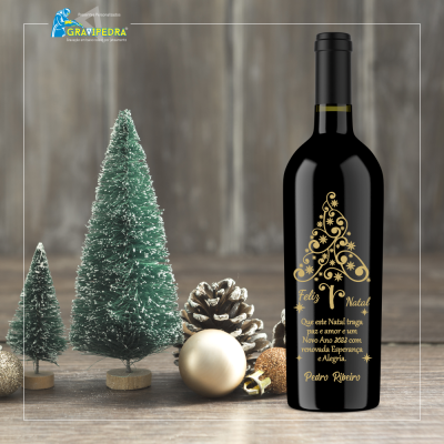 Garrafa de vinho com decoração dourada de Natal e pequenas árvores e bolas de Natal ao lado