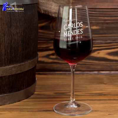 Copo de vinho com texto 'CARLOS MENDES SINCE 1976' ao lado de barril de madeira