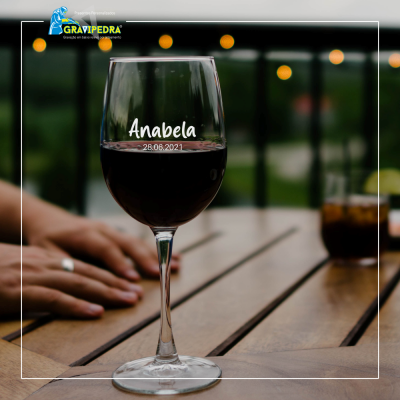 Taça de vinho tinto com nome personalizado na mesa de madeira ao ar livre