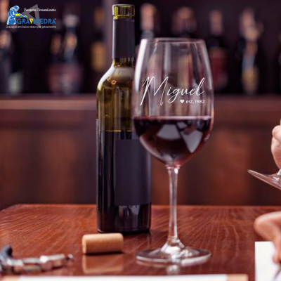 Garrafa de vinho com taça de vinho tinto e texto branco Migal est. 1982 sobre a taça.