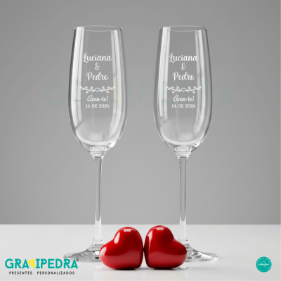 Duas taças de vidro com gravação e corações vermelhos em fundo cinzento