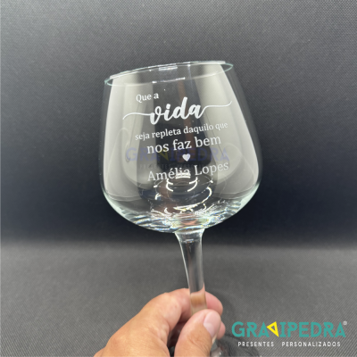 Copo de vinho transparente com texto branco personalizado em fundo escuro