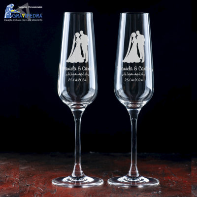 Duas taças de champanhe transparentes com gravações de casal de noivos e texto personalizado