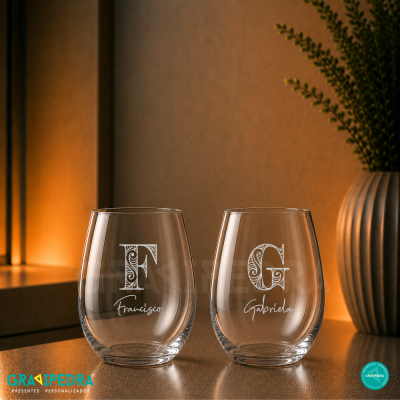 Duas taças de vidro personalizadas com nomes e iniciais decorativas em ambiente quente
