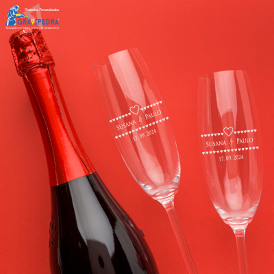 Garrafa de espumante e dois copos gravados com nome e data em fundo vermelho