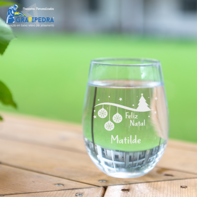 Copos de vidro transparente com gravação branca de Natal numa mesa de madeira