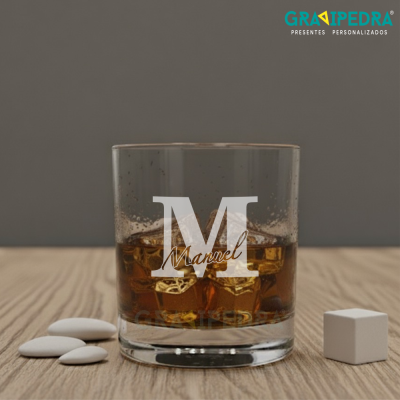 Copo personalizado com gelo dourado e nome Manuel, sobre madeira clara com pedras brancas