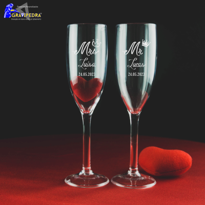 Dois copos de champanhe gravados com texto e data ao lado de um coração vermelho