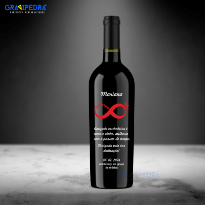 Garrafa de vinho preta personalizada com texto branco e símbolo vermelho, sobre superfície branca e fundo cinza.