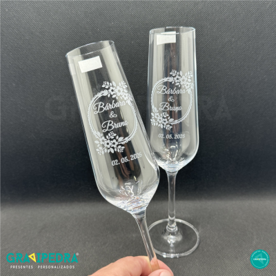 Dois copos de champanhe transparentes com nomes e data personalizados.