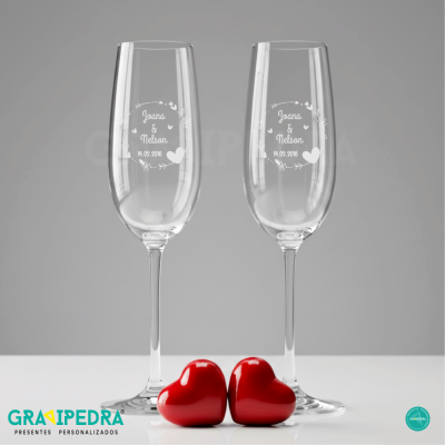 Dois copos de champanhe personalizados com nomes e data, e dois corações vermelhos em baixo.