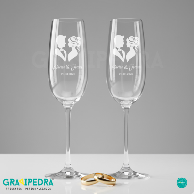 Dois copos de champanhe com decoração de casal e data, com dois anéis dourados ao centro