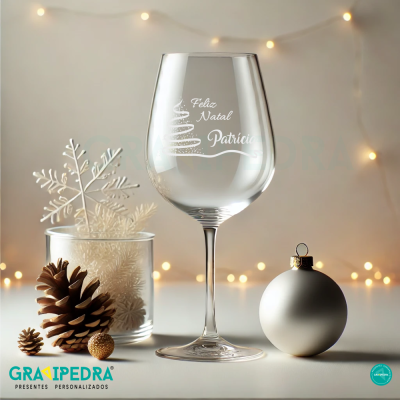 Copo de vinho transparente com gravação de Natal em ambiente decorativo festivo
