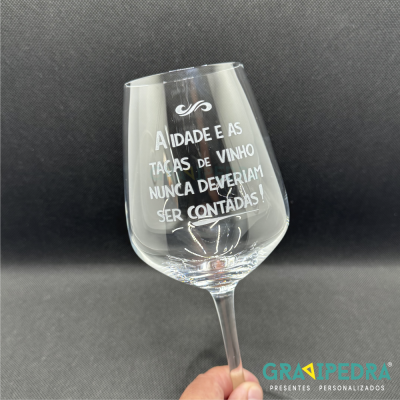 Copo de vinho transparente com texto gravado em branco