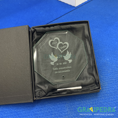 Placa de vidro gravada com texto e imagens dentro de caixa preta