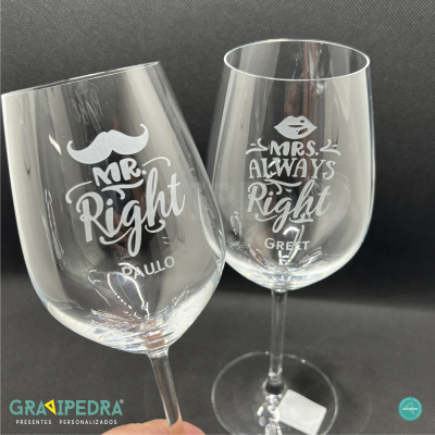 Dois copos de vinho transparentes com gravação personalizada em fundo preto.
