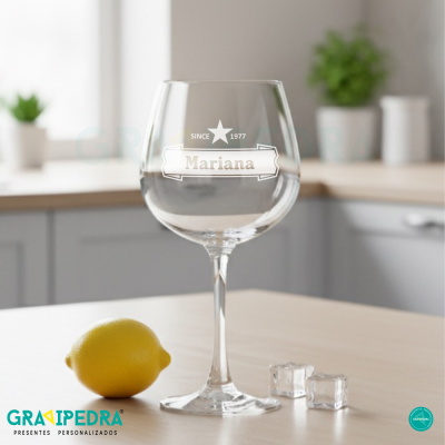 Taça de vinho personalizada com texto em branco sobre bancada com limão e cubos de gelo