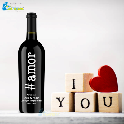 Garrafa de vinho com texto personalizado ao lado de cubos de madeira e coração vermelho