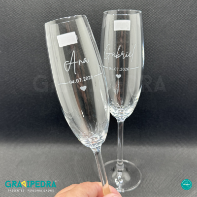 Dois copos de vidro tipo champagne com gravações personalizadas.