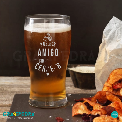 Copo de cerveja com texto impresso e snacks ao lado sobre madeira