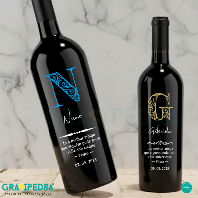 Duas garrafas de vinho tinto com rótulos personalizados e texto em português num fundo de mármore branco.